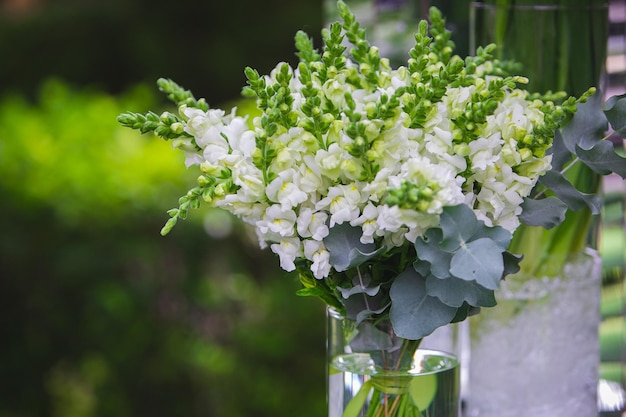 Weiße Vase mit Blumen in einem Restaurant serviert Tisch Korb mit Blumen Kibana Hochzeitsfloristik