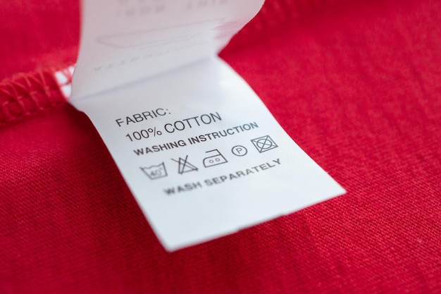 Foto weiße wäschepflege waschanleitung kleideretikett auf rotem baumwollhemd