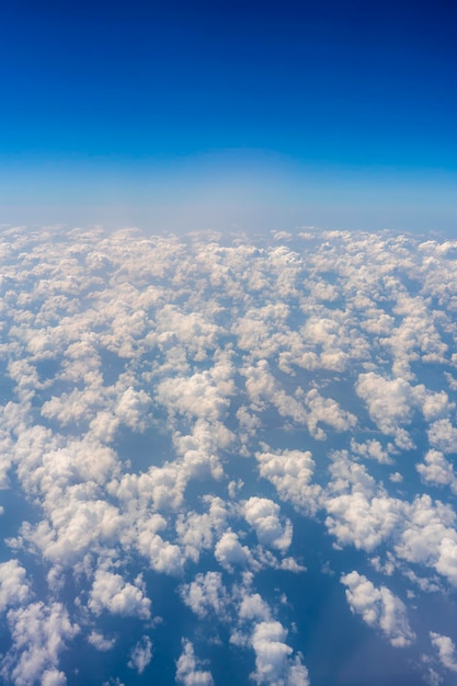 Weiße Wolken und blauer Himmel ein Blick aus dem Flugzeugfenster