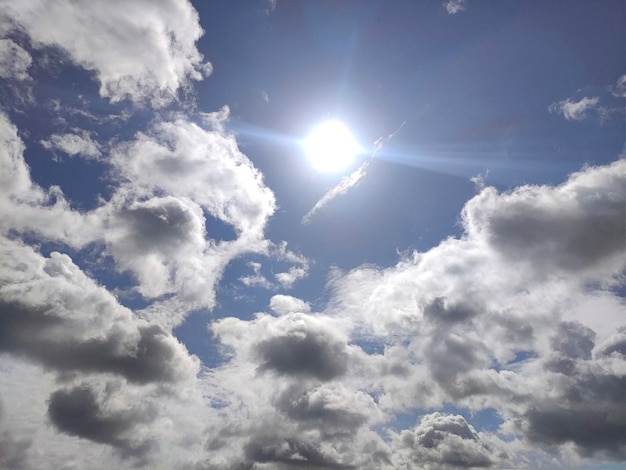 Weiße Wolken und Sonne über blauem Himmelshintergrund. Flauschige Cumuluswolken formen Foto