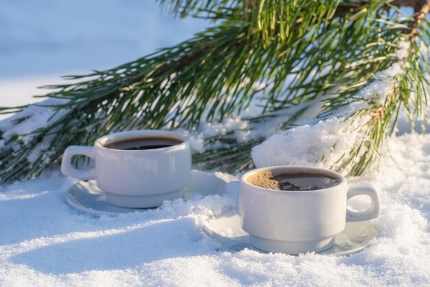 Weiße zwei Tasse heißen Kaffee auf einem Bett aus Schnee und weißem Hintergrund hautnah