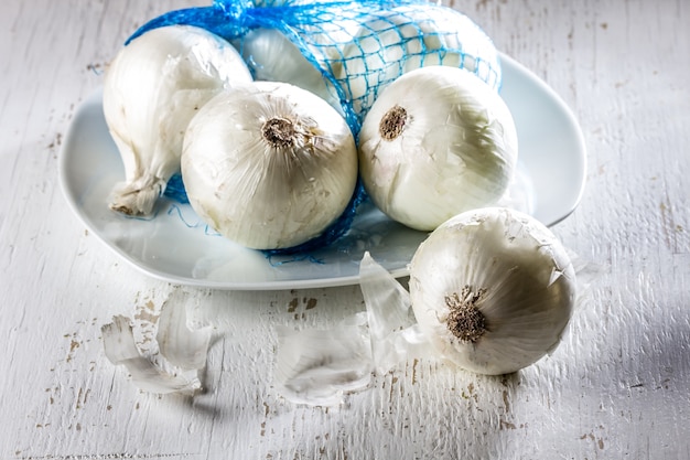 Weiße Zwiebel auf weißer Platte, hölzerner Hintergrund