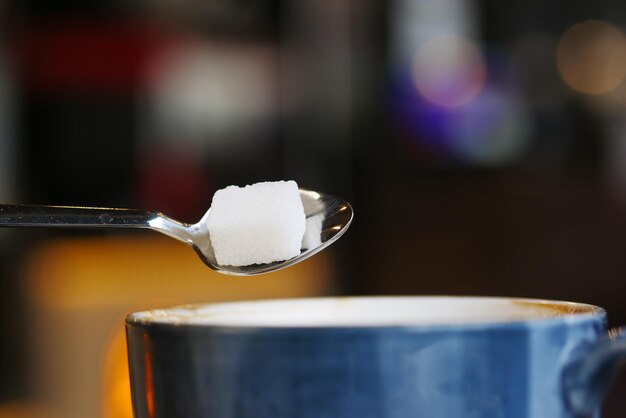 Weißen Würfelzucker in eine Kaffeetasse gießen