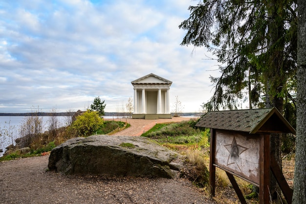 Weißer antiker Pavillon, der Tempel von Neptun in Mon Repos-Landschaft durch den See Wyborg errichtet