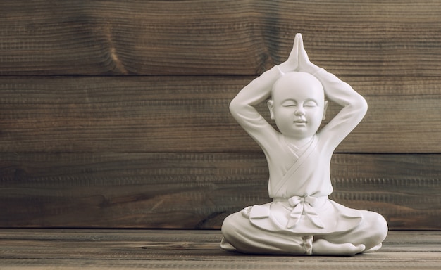 Weißer Buddha. Mönchskulptur auf hölzernem Hintergrund. Meditation und Entspannung