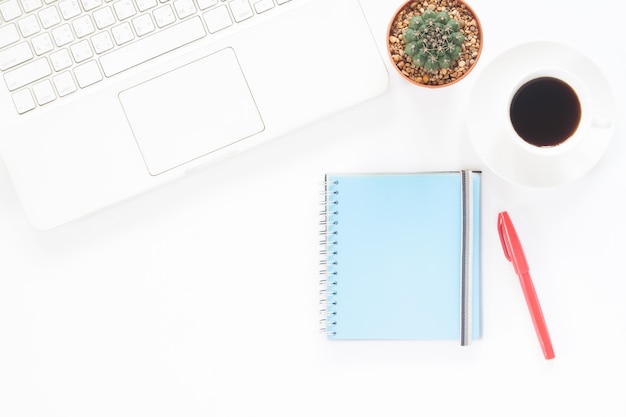 Weißer Computer Laptop mit Kaffeetasse, Notebook und Kaktus auf weißem Schreibtisch, Workspace Konzept