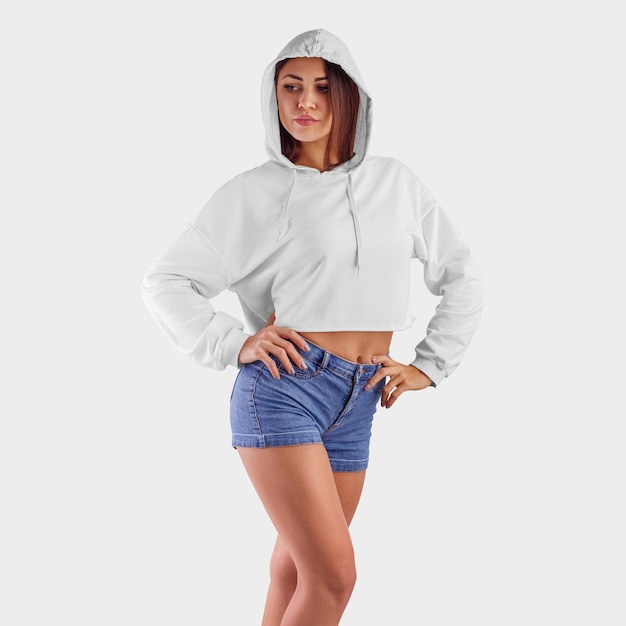 weißer Crop-Top-Hoodie auf einem jungen schönen Mädchen in blauen Shorts zur Präsentation des Designs