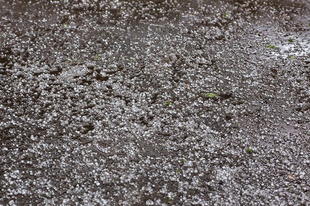 Weißer Eishagel auf der Asphaltstraße nach Sommersturm bei Tageslicht