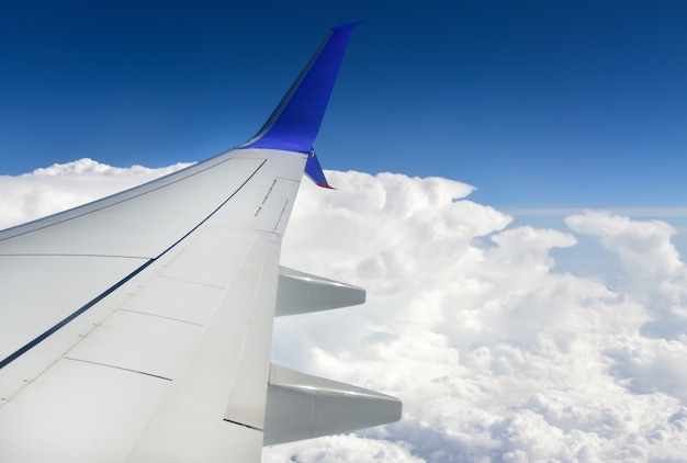 Weißer Flugzeugflügel vor dem Hintergrund der Wolken am Himmel.
