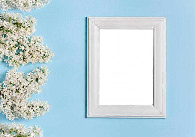 Weißer Fotorahmen und lila Blumen auf einer blauen Wand.