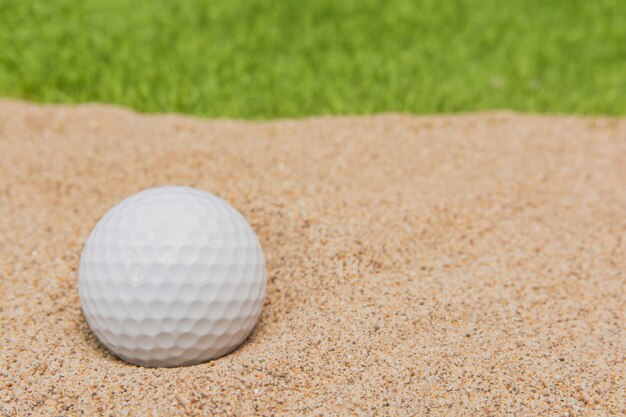 Weißer Golfball im Sandbunker auf Golfgericht