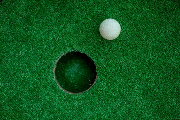 Weißer Golfball in der Nähe des Lochs Der Golfball am Loch