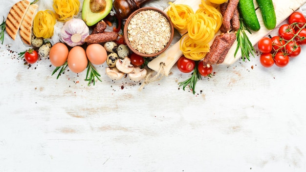 Weißer Hintergrund aus Holz Lebensmittel Tomaten Pasta Gewürze Gemüse und Würstchen Ansicht von oben