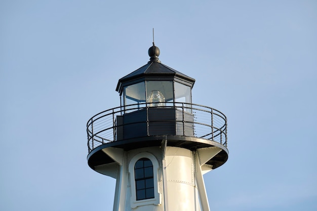 Weißer hoher Leuchtturm am Meeresufer gegen den blauen Himmel für die Navigation von Handelsschiffen