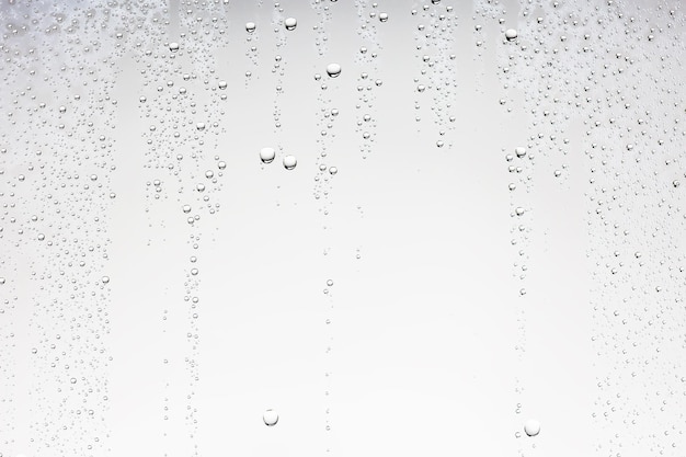 Foto weißer isolierter hintergrund wassertropfen auf dem glas / nasses fensterglas mit spritzern und wassertropfen und kalk, textur herbsthintergrund