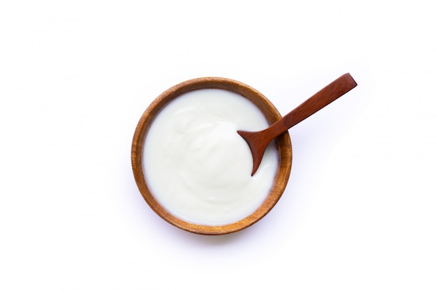 Weißer Joghurt in der Holzschale auf weißem Hintergrund.