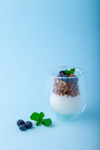 Weißer Joghurt und Müsli mit frischen Erdbeeren, Blaubeeren, Minze im Glas