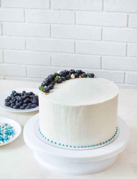 Weißer Kuchen verziert mit Blaubeeren und Süßigkeiten auf einem Ständer mit Kopierraum.