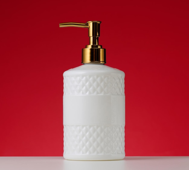 Weißer Kunststoffbehälter mit goldenem Spender auf rotem Hintergrund Behälter für flüssiges Seifenshampoo