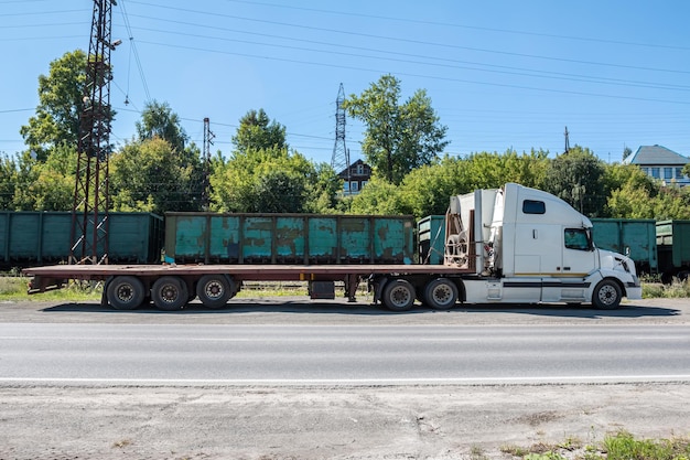 Foto weißer langstrecken-lastwagen mit anhänger an einem güterbahnhof auf dem land