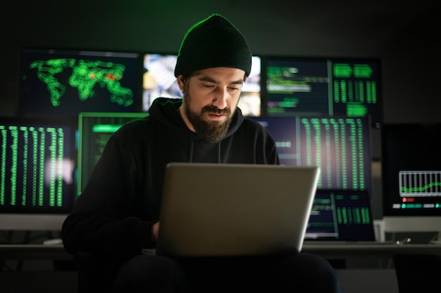 Foto weißer männlicher hacker, der laptop benutzt, um einen malware-angriff im globalen maßstab zu organisieren