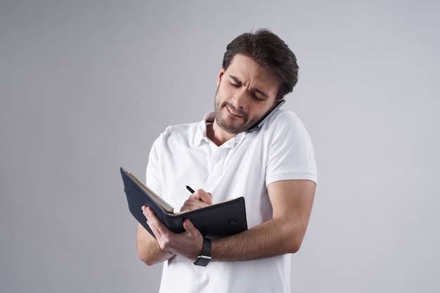 Weißer Mann, der am Telefon mit dem Notizbuch lokalisiert spricht.