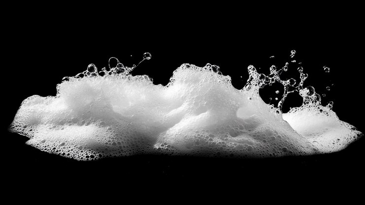 Weißer Schaum springt in die Luft und erzeugt dynamische Texturen auf schwarzem Hintergrund
