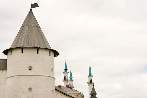 Weißer Steinturm mit einem spitzen Holzdach und einer schönen Moschee im Hintergrund