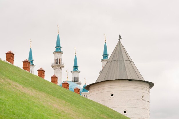 Weißer Steinturm mit einem spitzen Holzdach und einer schönen Moschee im Hintergrund