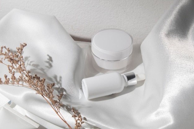 Weißer Stofftextilhintergrund mit Lebensstil, kosmetisches Make-up-Flaschenlotionscremeprodukt mit Schönheitsmode-Hautpflegegesundheitsmodell