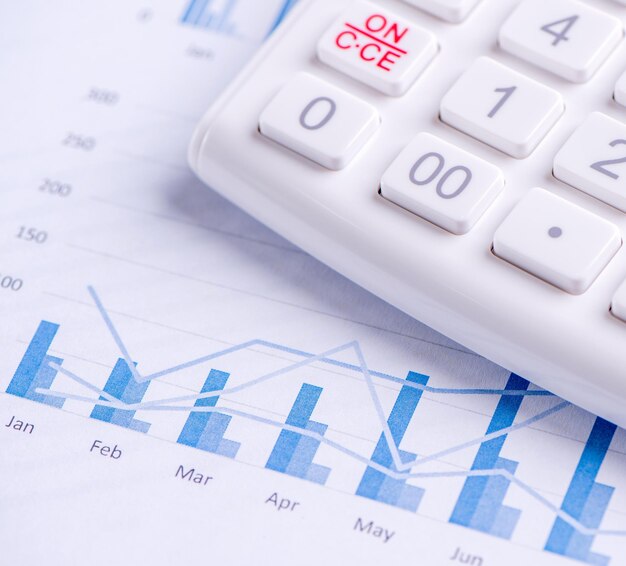 Weißer Taschenrechner und Bericht mit Diagramm- und Diagrammkonzept des jährlichen Finanzgewinnüberblicks Banking und Investition Nahaufnahme Kopienraum Makro