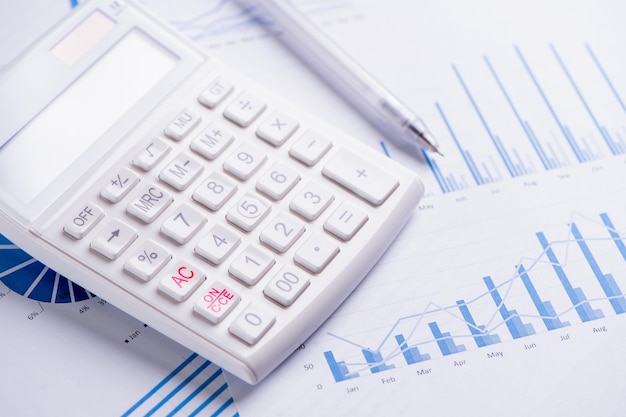 Weißer Taschenrechner und Bericht mit Diagramm- und Diagrammkonzept des jährlichen Finanzgewinnüberblicks Banking und Investition Nahaufnahme Kopienraum Makro