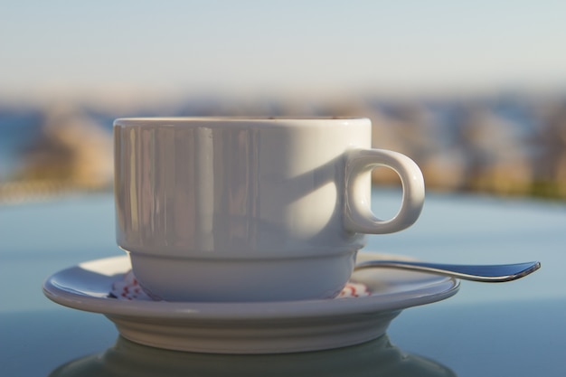 Foto weißer tasse kaffee auf dem tisch in meer. sommerferien-konzept