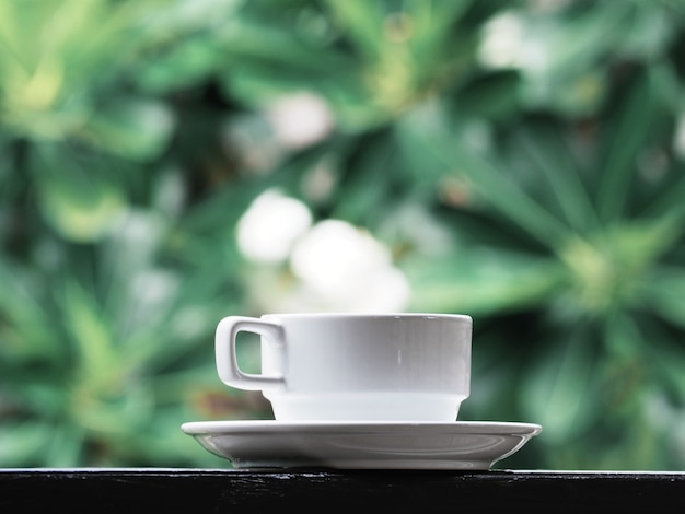 Weißer Tasse Kaffee über grünem Blumen.