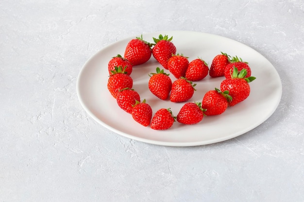 Weißer Teller mit Erdbeeren in Herzform, Konzept des Valentinstags, Draufsicht, Kopierraum