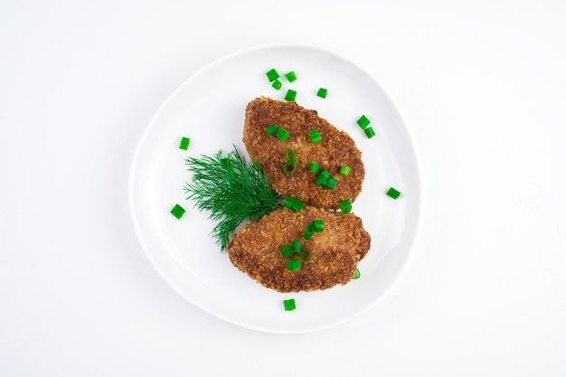 Weißer Teller mit gebratenen Schnitzeln und Kräutern auf Weiß