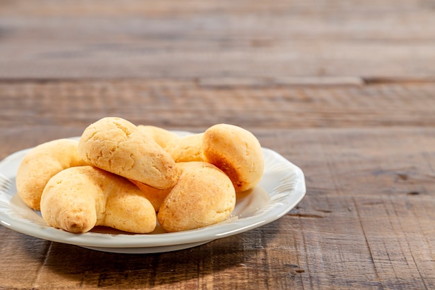 Weißer Teller mit Käsechipa, oben auf einem rustikalen Holztisch in Nahaufnahme