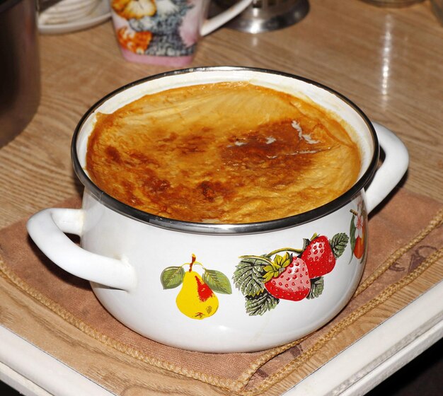 Weißer Topf mit gebackener Milch auf dem Tisch