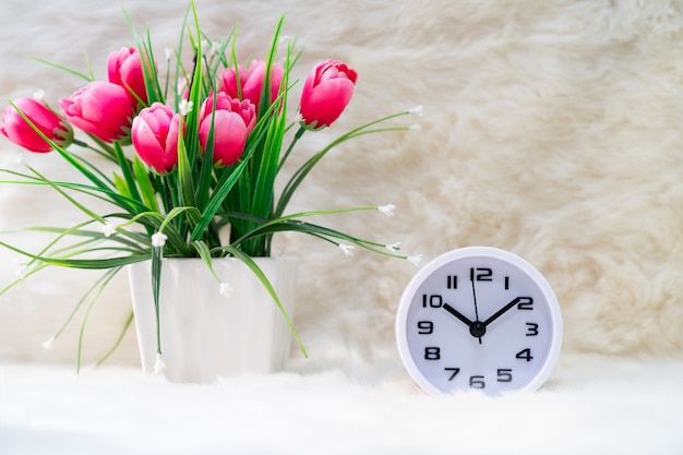 Weißer Wecker und Blume in der Vase auf Tisch