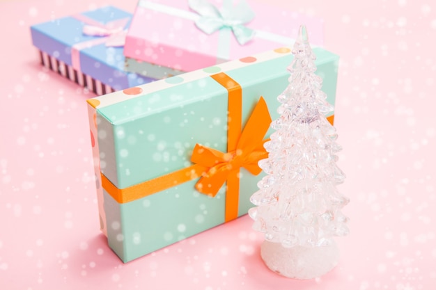 Weißer Weihnachtsbaum aus Glas mit Geschenken mit Schleifen auf rosa Hintergrund
