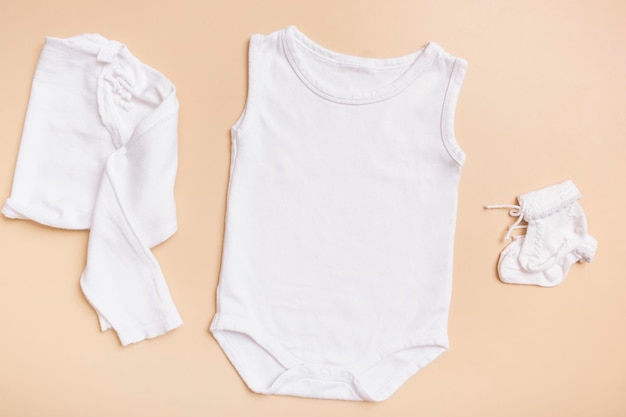 Weißes Baby-Bodysuit-Modell für Logo-Text oder Design auf beigem Hintergrund mit Draufsicht der Kleidung