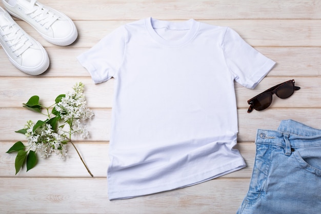 Weißes Baumwoll-Baumwoll-T-Shirt-Modell mit Flieder, Blue Jeans, Sportschuhen und Sonnenbrille. Design-T-Shirt-Vorlage, T-Shirt-Druck-Präsentationsmodell