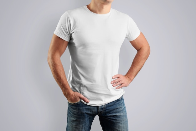weißes Baumwoll-T-Shirt auf einem jungen Mann, der an einer grauen Wand posiert.