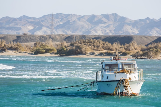 Weißes Boot mit vielen Seilen im Meer mit Bergen aus der Wüste in Ägypten