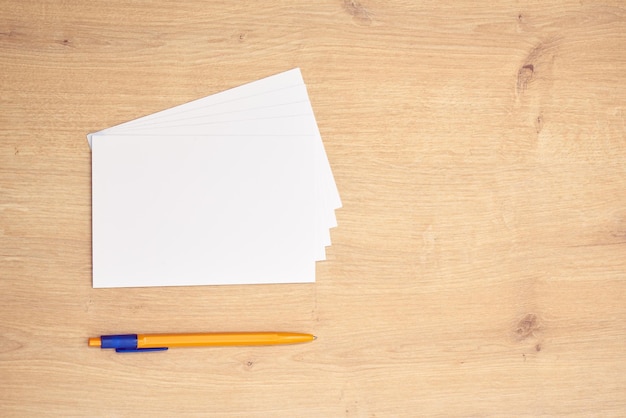 Foto weißes briefpapier oder karten und ein gelber stift auf einem holztisch. banner beachten.