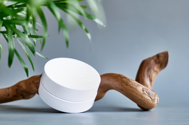 Weißes Cremeglas auf Holzhaken auf pastellgrauem Hintergrund Präsentationsbühne für Kosmetikproduktwerbung Ecobio-Kosmetikkonzept Beauty-Produktwerbung trendiges minimalistisches Mockup