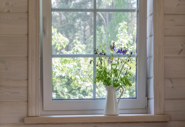 Weißes Fenster mit Mosuito-Netz in einem rustikalen Holzhaus