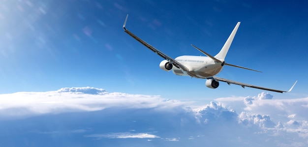 Weißes Flugzeug, das über blauen Himmel und Wolken fliegt