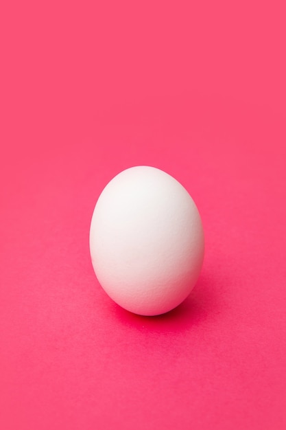 Weißes frisches Hühnerei auf rosa Oberfläche
