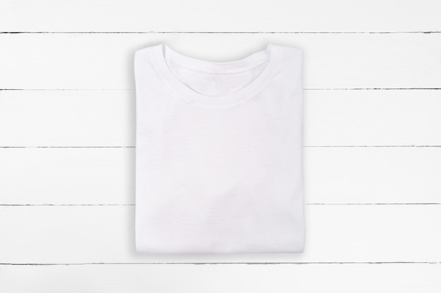 Weißes gefaltetes leeres T-Shirt auf weißem hölzernem Hintergrund